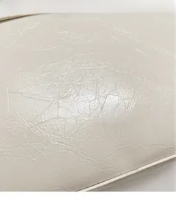 Detailed macro shot showing the premium crinkled texture of the creamy white handbag fabric