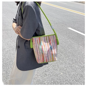 Detail of colorful striped canvas bucket bag with vibrant green trim and shoulder strap