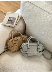 Détail de deux sacs Boston en cuir beige et vert gris posés sur un canapé chic
