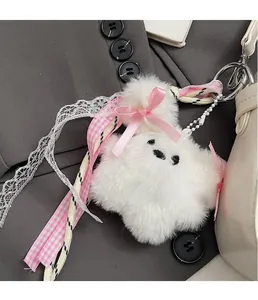 Detail of soft white plush charm with pink plaid ribbon and lace on a handbag