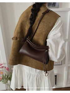 Détail du sac à bandoulière marron vintage avec plis incurvés et anneau en métal