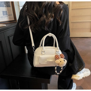 Detailed view of a white bow bowling bag with a plush puppy charm and bow accent