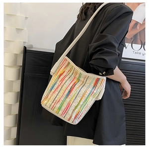 Detail of colorful striped woven bucket bag with cream shoulder strap on model