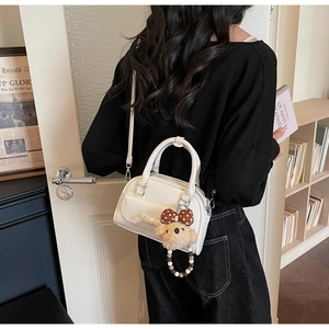 Lifestyle view of white bow handbag with teddy bear charm worn by a model in a library