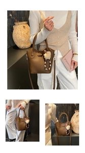 Detail view of brown pebbled leather bucket bag with top handles and sheep charm