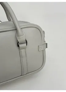 Détail d'un sac à main vert sauge en similicuir avec poignées rondes et texture lisse