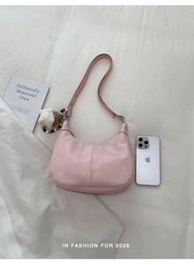 Détail du sac hobo demi-lune rose pâle avec texture en cuir lisse et pendentif mouton
