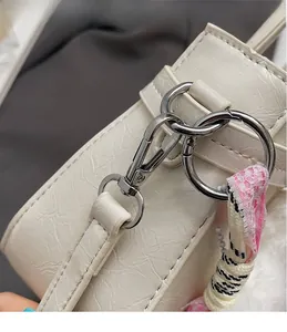 Detail of silver metal hook and cream textured leather with silk scarf accent