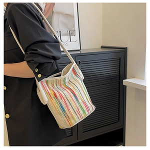 Detail of colorful striped fabric and white leather strap on a stylish bucket bag