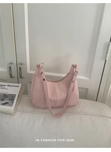 Vue détaillée du sac selle rose clair avec rivets argentés et fermeture éclair sur tissu