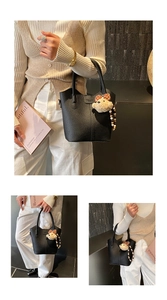 Close-up of black litchi grain leather bucket bag with cute bear and wooden bead charms