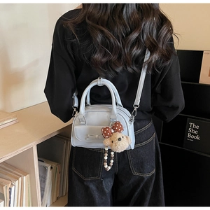 Detail of light blue bow handbag with teddy bear charm on a female model