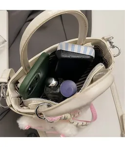 Top view of cream bucket bag with crocodile texture, striped lining, and interior storage