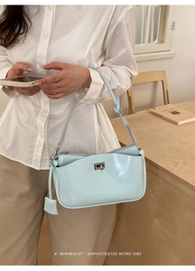 Close-up of light blue patent leather shoulder bag featuring a silver metal twist lock