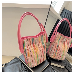 Detailed shot of pink striped canvas bucket bag with colorful vertical patterns and leather trim