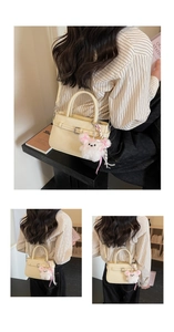 Detail of cream crossbody bag featuring a decorative metal buckle and plush bear charm