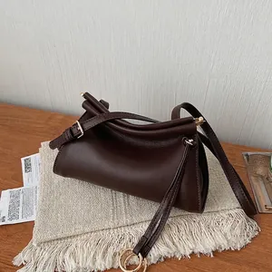 Detail view of smooth dark brown leather bag with fold design and gold metal buckle