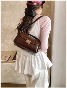 Détail du sac bandoulière vintage en cuir marron foncé avec fermoir en métal sur modèle