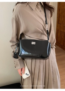 Detail of classic black baguette bag with silver twist lock and minimalist leather strap