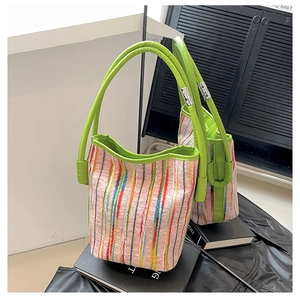 Detail of colorful striped woven bucket bag with vibrant green leather handle and silver buckle