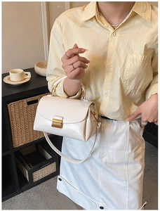 Vue détaillée d'un sac à bandoulière en cuir blanc avec un fermoir métallique doré carré