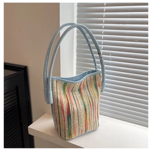 Detail of multi-color striped woven bucket bag with light blue leather straps by a window