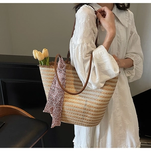 Straw woven tote bag with brown leather handles and decorative paisley silk scarf