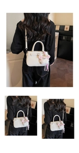 Detail of elegant cream faux leather handbag with detachable strap and plush charm
