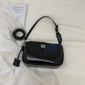 Detail of black glossy baguette bag featuring silver metal twist lock and strap
