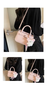 Detailed view of pink crossbody square bag with belt buckle and cute plush bear charm