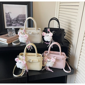 Detailed group view of colorful crossbody bags with cute plush doll charms and belt buckle detail