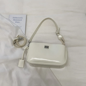 Detail view of cream white baguette bag with silver twist lock and dual strap options