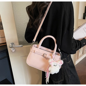 Pink leather crossbody bag detail featuring adjustable strap and a cute white teddy charm