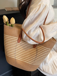 Large striped straw tote bag with brown leather handles for beach or commute