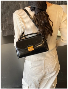 Détail du sac à bandoulière en cuir verni noir avec fermoir carré en métal doré
