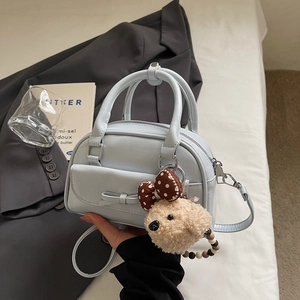 Detail of light blue bow handbag with cute plush bear charm in a lifestyle setting