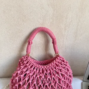 Details der rosa geflochtenen Baumwolltasche mit weißer Perlenkette und Tragegriff