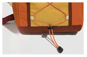 Detail of outdoor backpack showing orange elastic drawstring and black plastic toggle closure