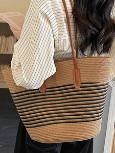 Large woven straw tote bag with black stripes and brown leather straps for beach holidays