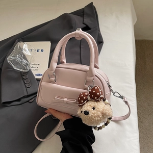 Detail of light pink mini bowling bag featuring a bow pocket and cute plush bear charm