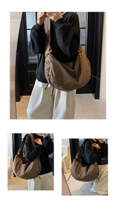 Détail d'un grand sac bandoulière marron plissé avec œillets métalliques et lacets