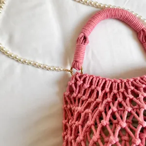 Détail du sac en maille rose tissé main avec poignées en corde et chaîne de perles blanches