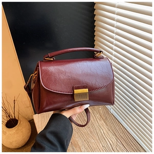 Vue détaillée du sac bandoulière vintage bordeaux avec boucle dorée et texture cuir