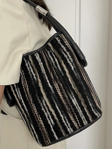 Chic striped knit bucket bag with black leather straps and silver metal hardware details