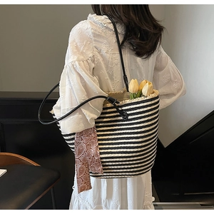 Detail of hand-woven straw tote with black stripes and decorative floral silk scarf handle