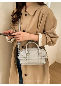 Détail d'un sac Boston gris clair avec boucle décorative et bandoulière réglable en PU