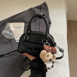 Detail of black bow bowling bag with plush bear charm and beaded strap accents