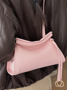 Minimalist soft pink cloud crossbody bag with gold hardware shown on a model