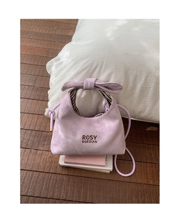 Detail of lavender suede handbag showing bow handle knot and striped fabric lining
