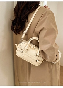 Sac à main bowling beige minimaliste avec bandoulière porté sur un trench-coat